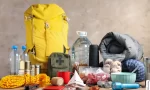 how to start prepping An emergency kit including bug-out bag, first aid kit, water, and others.